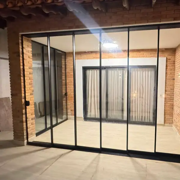 Portas de correr com perfil preto e parede de tijolinho, na Vila Madalena, obra da PS do Vidro